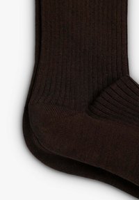 Calzini lavorati a maglia marroni con una texture a coste, dotati di punta e tallone rinforzati per una maggiore durata. Il materiale è morbido e flessibile.