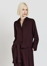Chemise bordeaux à manches longues avec une fermeture à boutons sur le devant, un col et une coupe décontractée. Comprend une ceinture assortie et une texture de tissu douce.