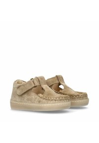 Beige suède kinderschoenen met een klittenbandsluiting en uitsparingen, met een gestructureerd oppervlak en contrasterende stiksels. Rubberen zool.