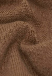 Brunt strikket stof med en blød tekstur, der har et subtilt ribmønster. Materialet virker varmt og en smule fuzzy.