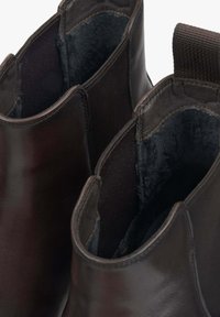 Ciemnobrązowe skórzane botki za kostkę z gładką powierzchnią, miękką czarną podszewką i elastycznym panelem bocznym dla łatwości zakładania.