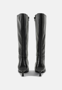 Knee-high black leather boots with a smooth texture, tapered heels, and side zippers. Features a fitted design and subtle stitching details.