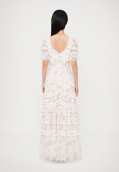 Biele maxišaty s kvetinovou potlačou, s nariasenou textúrou, krátkymi nadýchanými rukávmi a výstrihom do V na chrbte. Jemné, priehľadné vrstvy vytvárajú hĺbku a pohyb.