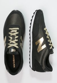 Czarne sneakersy z siateczkowego i zamszowego materiału. Złote akcenty na logo i sznurowadłach. Biała podeszwa środkowa z teksturowaną gumową podeszwą zewnętrzną dla lepszej przyczepności.