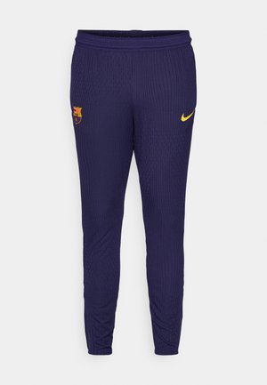Navy athletic pants with ribbed texture, yellow Nike logo, and Barcelona club crest on the thigh. Elastic waistband for comfort.