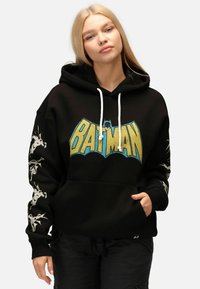 Felpa nera con una grande grafica blu e gialla "BATMAN"; presenta lacci bianchi e disegni grigi sulle maniche. Materiale in cotone, tasca a marsupio.