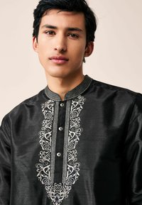 Black kurta made of satin, featuring intricate white floral embroidery along the placket and collar, with a button closure.