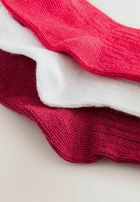 Drei gefaltete gestrickte Socken in Rosa, Weiß und Dunkelrot auf einer hellen Oberfläche, die ein geripptes Muster und Kanten zeigen.