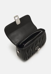 Czarna pikowana skórzana torebka z metalowym zapięciem, charakteryzująca się gładkim wnętrzem i dwoma zamykanymi na zamek przegrodami.