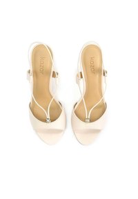 Beige slingback-korkokenkiä ohuilla remmeillä, pyöreällä avonaisella varpaalla ja pienellä koristekivellä edessä. Sileä nahkapinta.