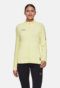 Giacca gialla con cerniera e collo alto, con logo sul petto a sinistra, due tasche laterali e cuciture a contrasto. Tessuto dalla texture liscia.