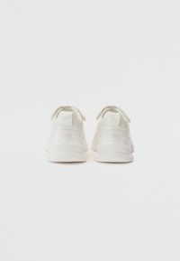 Baskets de sport blanches avec une tige lisse et texturée, un talon arrondi, des lacets élastiques et un soutien rembourré à la cheville. Design minimaliste, lignes épurées.