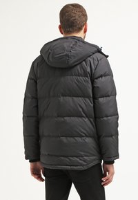 Svart puffjacka med huva, med horisontella kviltade sektioner, elastiska muddars och en avslappnad passform, tillverkad av vattenavvisande material.