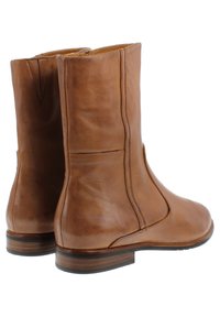 Bottines en cuir tan avec une finition lisse, des coutures latérales et un léger talon. Dotées d'une fermeture éclair pour un enfilage facile.