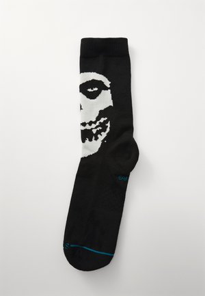 Black socks featuring a white skull design, with accents around the eyes and teeth. Made of a soft material, with a ribbed cuff.