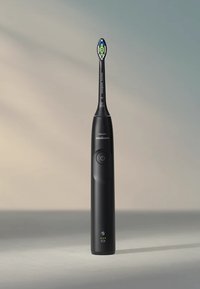 Spazzolino elettrico nero con manico slim, testa rotonda e pulsante di controllo illuminato. Presenta un design colorato sulla testa dello spazzolino.