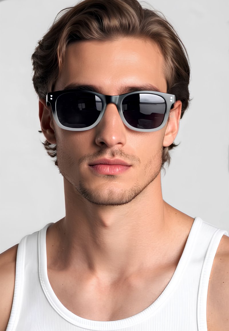 Occhiali da sole con montatura nera e dettagli grigi, lenti scure, forma rettangolare e finitura opaca, indossati da un modello in una canotta bianca.