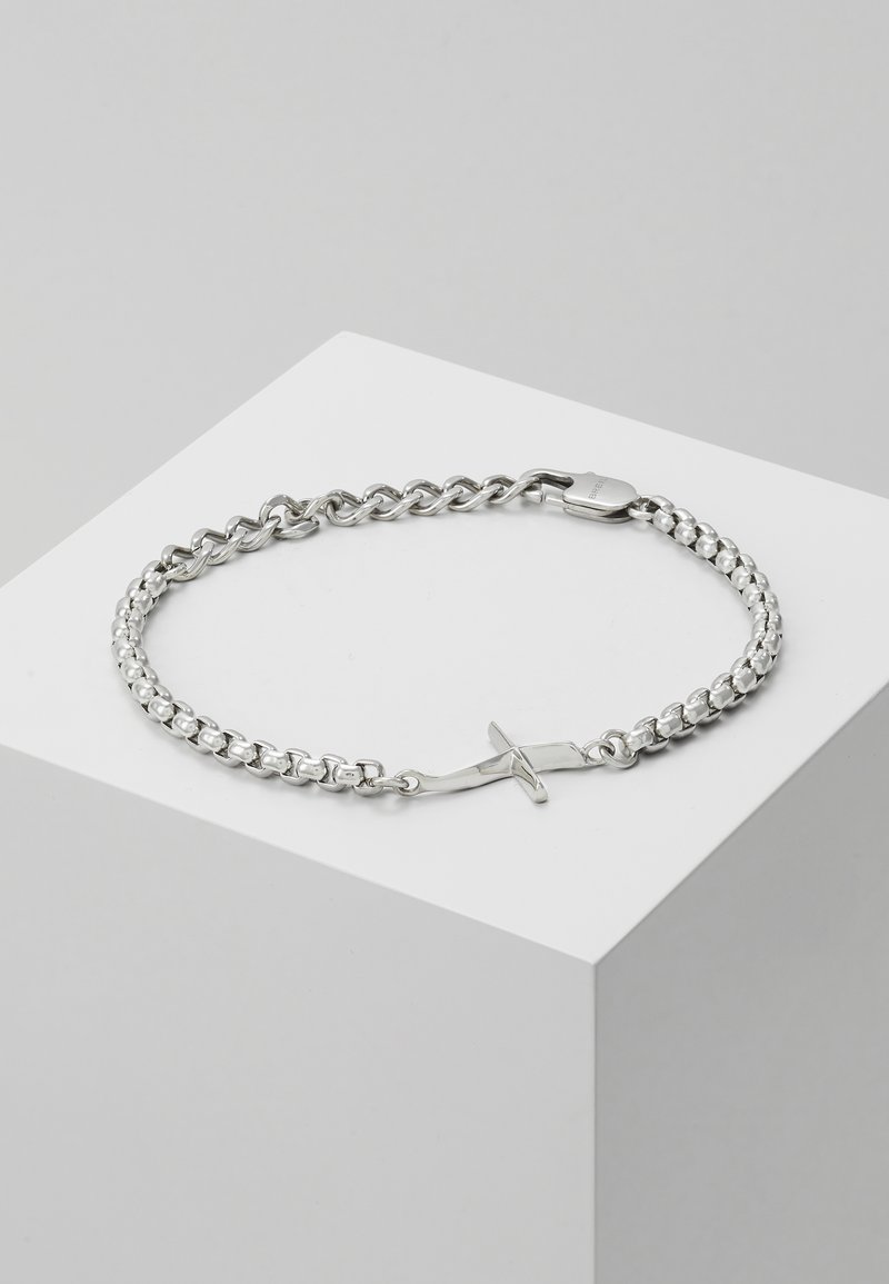 Pulsera de cadena de plata con eslabones entrelazados, una textura suave y un diseño de cierre único con forma de cruz.