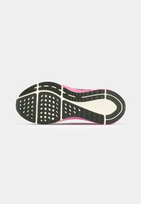 Semelle de chaussure de sport en caoutchouc noir avec un motif de grip texturé, semelle intermédiaire blanche et accent rose le long des bords.
