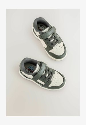 Sneakers verdi e bianchi con strap in velcro e lacci, visti dall'alto. Presentano un design decorativo all'interno della scarpa.