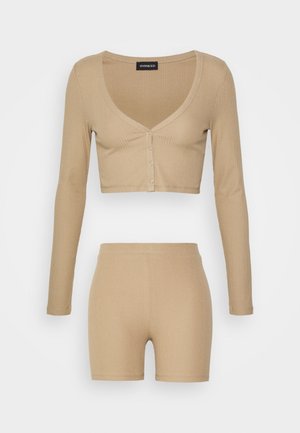 Set beige a due pezzi in maglia a coste con top cropped con maniche lunghe e bottoni e pantaloncini aderenti a vita alta.