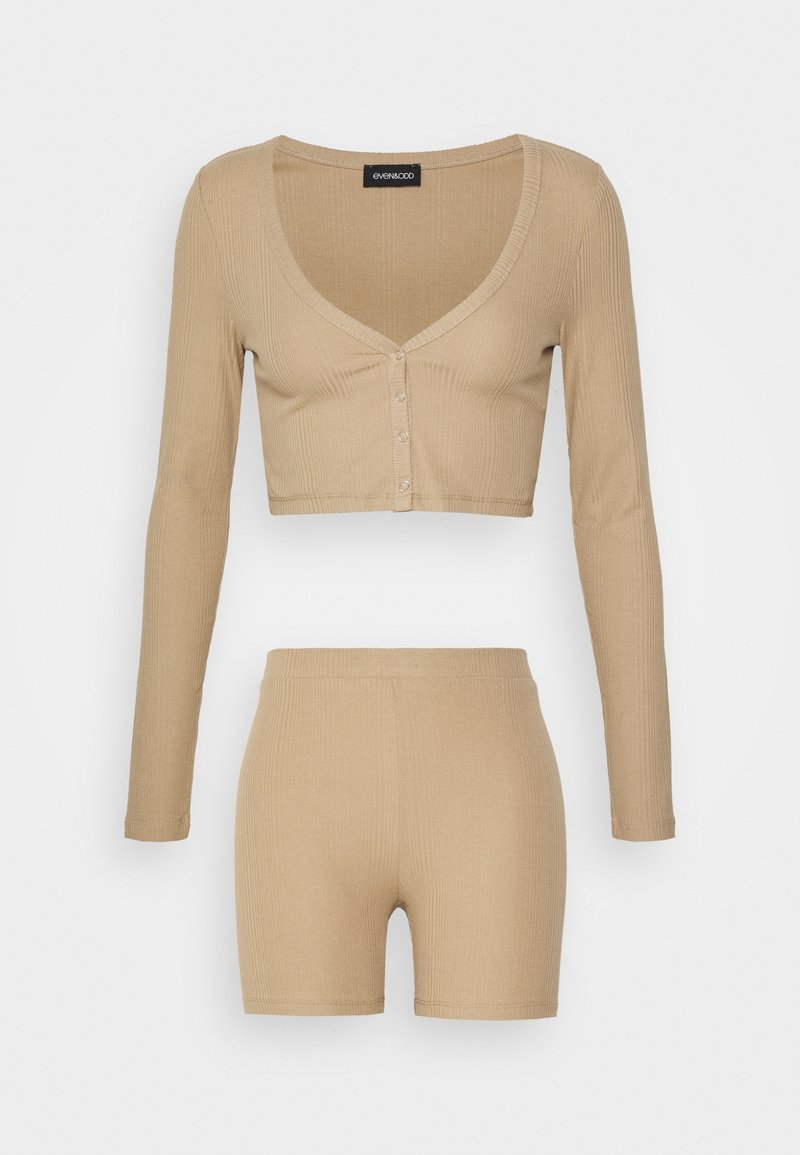 Ensemble deux pièces en maille côtelée beige avec un haut boutonné court à manches longues et un short ajusté taille haute.