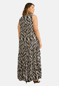 Maxiklänning i svart och beige djurmönster, med ärmlös design och lager av volanger i nederkant. Slät tyg med en flödande silhuett.