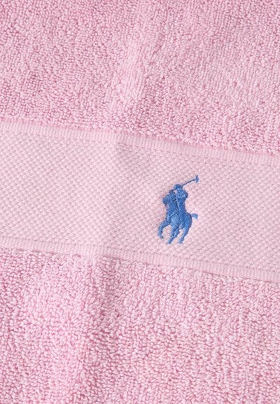 Απαλό ροζ πετσέτα από πετσέτα με υφασμένη ταινία και μικρό μπλε κεντητό λογότυπο ενός παίκτη πόλο επάνω σε άλογο.