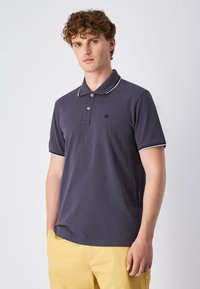 Marineblaues Polohemd aus Baumwolle, mit einer Dreiknopf-Leiste, weißen Kontrastelementen am Kragen und den Ärmeln sowie einem kleinen Logo auf der Brust.
