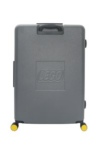 Gray hard-shell suitcase with a textured surface, featuring a prominent LEGO logo, sturdy handle, and yellow-accented wheels.