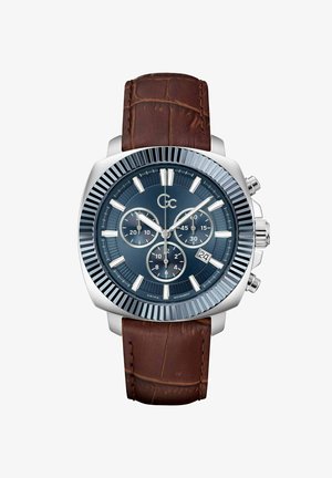 Hronogrāfs ar zilu ciparnīcu, sudraba korpusu un teksturētu brūnu ādas siksnu. Iezīmētas izteiktas atzīmes, subciparnīcas un datuma rādījums.