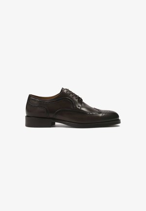 Chaussure oxford en cuir marron avec bout arrondi, détails brogue, cinq œillets et un petit talon empilé. Fini lisse avec des coutures accents.