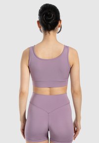 Conjunto de entrenamiento en un tono púrpura claro que incluye un sujetador deportivo ajustado con tirantes anchos y shorts de talle alto con una textura suave y costuras sutiles.