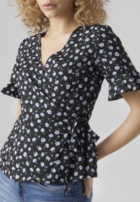 Top avvolgente nero a fiori con maniche corte, caratterizzato da motivi floreali blu e bianchi, dettagli con cintura da annodare e scollo a V.