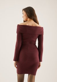 Sügavast burgundi tooni off-the-shoulder ribatud kleit, millel on pikad varrukad ja keha kujuga sobiv seelik.