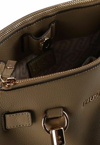 Innenraum einer olivgrünen Lederhandtasche mit Reißverschluss, goldfarbenen Beschlägen und gemustertem Futter. Enthält einen Verschluss und ein Logodetail.