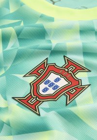 Portugal fodboldholds våbenskjold med rødt kors og blå skjolde på en grøn trøje med geometrisk mønster.