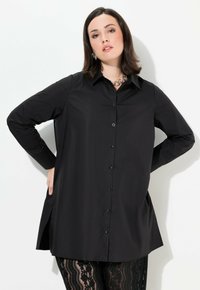 Camicia nera con bottoni, colletto, maniche lunghe e vestibilità comoda. Presenta aperture laterali e una texture del tessuto liscia.