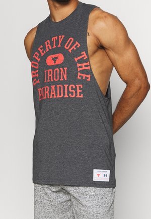 Homme portant un débardeur de sport gris foncé avec le texte rouge « Property of The Iron Paradise » et un logo, assorti à un short gris clair.