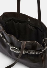 Ciemnobrązowa torba na ramię ze skóry z przestronnym, czarnym wnętrzem z tkaniny, ozdobiona srebrnym łańcuszkiem i zapięciem na zatrzask. Dwa solidne uchwyty.