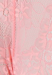 Tecido de renda rosa com padrões florais e um acabamento texturizado, com áreas de rede e seções sólidas criando um contraste visual.