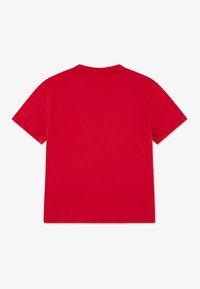 T-shirt en coton rouge avec un col rond et des manches courtes. Le tissu paraît lisse avec une couleur unie, sans motifs ni accents visibles.