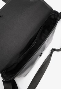 Borsa a tracolla nera in pelle con finitura liscia. Presenta un ampio interno in tessuto nero e una tracolla regolabile.