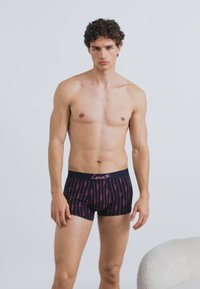 Fekete anyagú boxeralsó rózsaszín "Love" feliratos mintával, rugalmas derékpánttal, testhez simuló fazonnal és a comb közepéig érő hosszúsággal.