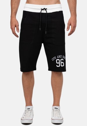 Shorts en coton noirs avec une taille élastique blanche et un cordon de serrage, comportant de grandes poches latérales et portant l'inscription "CIPO AND BAXX 96" en blanc.