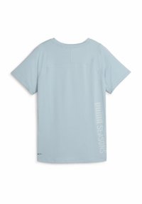 Světle modré tričko s krátkým rukávem, vyrobené z hladkého materiálu, s vertikálním potiskem "PUMA SEASONS" na pravé straně a volným střihem.
