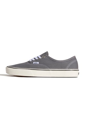 Zapatilla Vans gris de corte bajo con cordones blancos, suela de goma blanca y detalle de raya negra sobre fondo blanco.