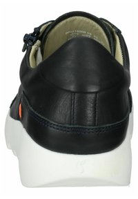 Zapatilla de cuero negro con suela de color claro. Presenta una forma redondeada, costuras en contraste y una lengüeta en el talón con un acento naranja. Incluye un detalle de cremallera.