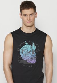 Svart ärmlös t-shirt med en färgglad dödskallegrafik som inkluderar musikgenrer och en cirkulär textdesign. Mjukt bomullsmaterial med en avslappnad passform.