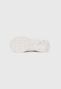Sola de ténis branca com um padrão de aderência de borracha texturizada e um design elegante e curvado. Minimalista, com bordas arredondadas e sem marcas visíveis.